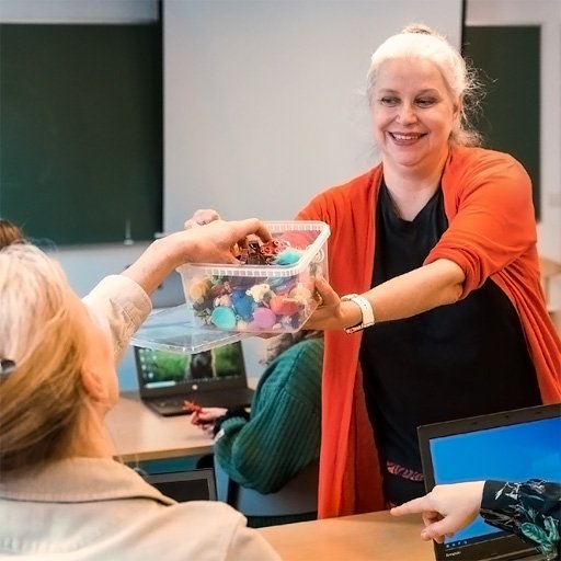 Kouluttaja ojentaa osallistujalle laatikon, jossa on harjoitusvälineitä.