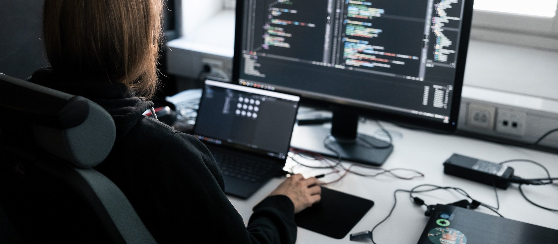An app developer works at a computer with two monitors.